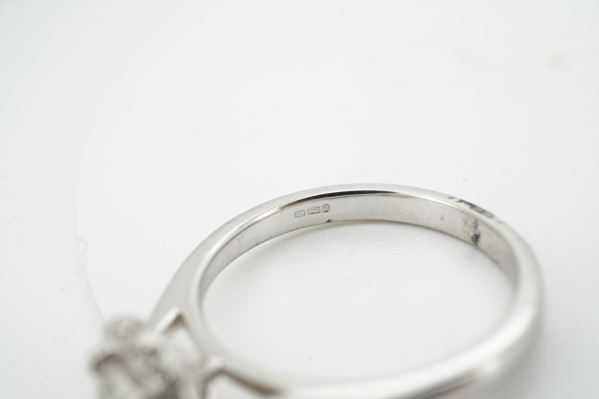 A diamond cluster ring, claw-set with a brilliant-cut diamond weighing approximately 0.70 carats, within a border of smaller brilliant-cut diamonds totalling approximately 0.10 carats, mounted in platinum, size M, Britis